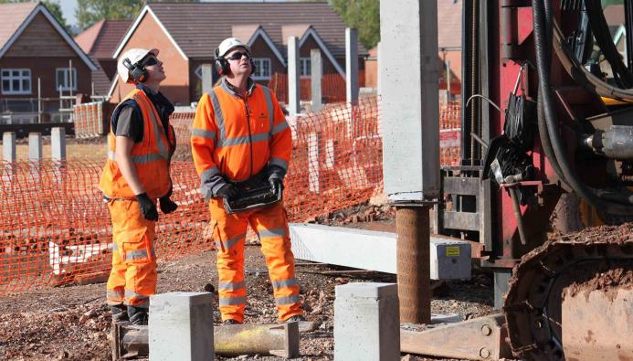 Two men installing concrete piles