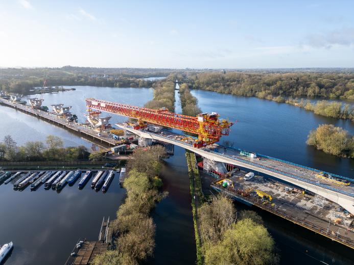 An aerial shot of a red bridge launcher crossing a river and canal