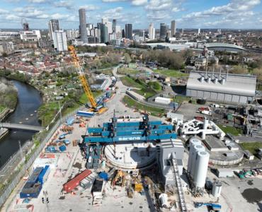 An aerial shot of a construction site with a yellow crawler crane and a large blue gantry crane