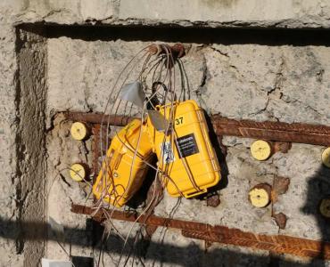 yellow boxes with lots of wires hanging on a newly poured concrete wall