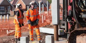 Two men installing concrete piles