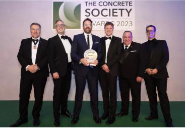 A group of men in dinner suits collect an award