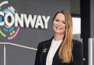 A woman standing in front of FM Conway's logo