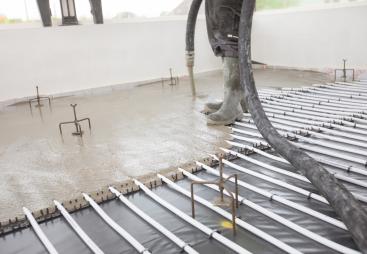 Concrete being poured inside a building over an underfloor heating system