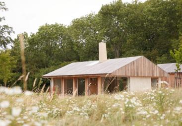 A small single storey house on the edge of a wood