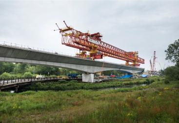 A picture of an orange launching girder sitting on top of an under construction railway viaduct