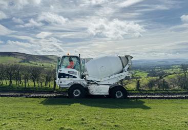 A white mobile concrete mixer in a green field