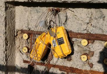 yellow boxes with lots of wires hanging on a newly poured concrete wall