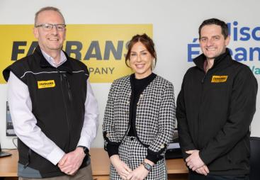 Three people, two men and a woman, standing with their hands clasped, looking at the camera