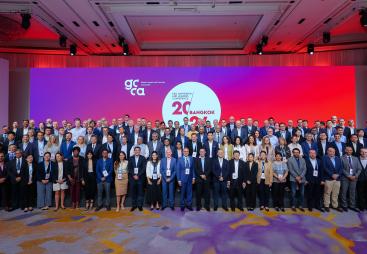 A large group of people standing infront of a white round sign and red lighting
