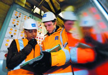 Two people in PPE looking at a laptop