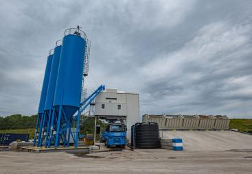 A concrete plant with three blue silos