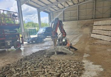 A demolition robot using a hammer to break a concrete floor