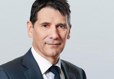 A head and shoulders picture of a man in a dark suit and tie