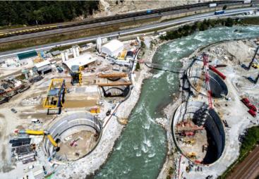 A large construction site divided by a bend in a river