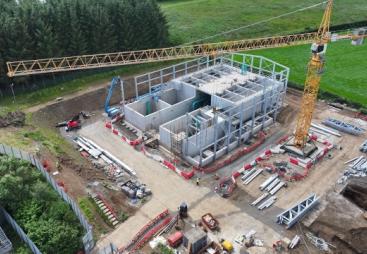 Aerial view of an under construction waste water treatment works with a yellow tower crane