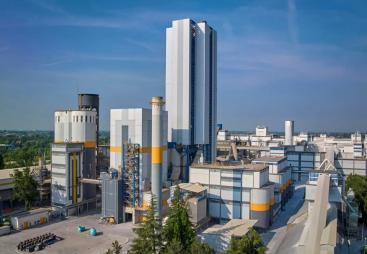 A white, grey and yellow cement plant against a blue sky