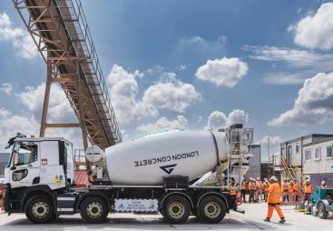 A white cement mixer and men in orange PPE
