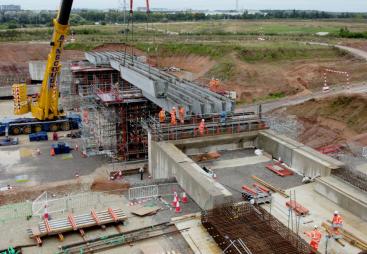 A construction site with a yellow crane and a bridge under constrcution