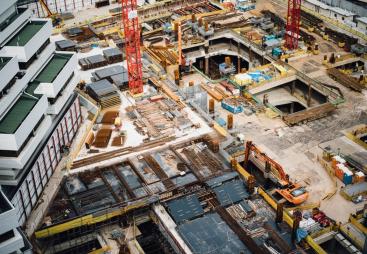 A construction site from above with a red tower crane and yellow excavators