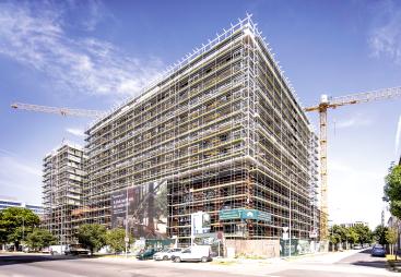 An under construction mid-rise building covered in scaffolding