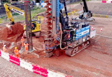 A blue piling rig and a yellow excavator at work on a construction site