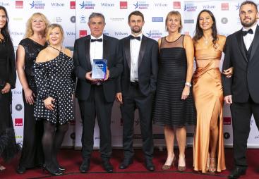 A group of people in evening wear in a line, on a stage accepting an award