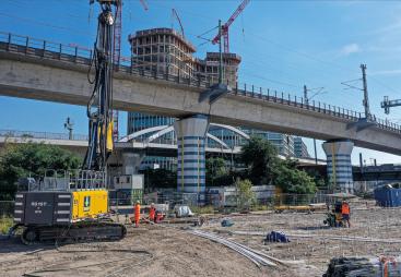A yellow piling rig stands in front of a bridge on a construction site in Germany