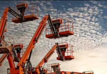 Orange aerial work platforms set against a backdrop of white, fluffy clouds