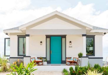 A white, single storey house with a green door