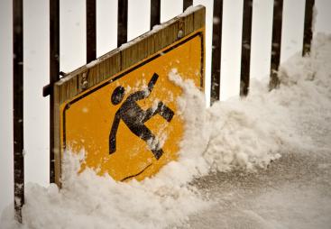 A health and safety sign of a person slipping on ice, covered in snow