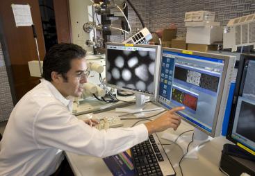 A man in lab clothes looking at monitors in a laboratory