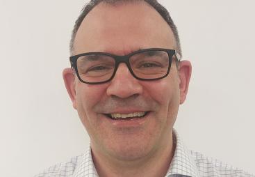Head and shoulders picture of a smiling man in glasses