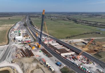 An aerial view of three cranes as the prepare to install bridge beam on the A43 for HS2, March 2025.