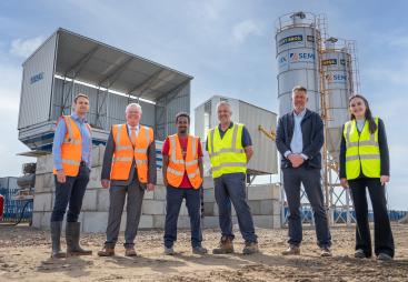 L–R: Prof. David Hughes; Bob Borthwick; Scott Bros recycling innovation engineer Feysal Shifa; Peter Scott; Joss Newberry; and Cassidy Smith, Teesside University’s IP and commercialization manager, standing in front of Scott Brothers new low-carbon concrete plant in Teeside.