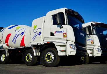 Two of Cemex's new electric trucks, which are designed for urban use, offering up to a 100% reduction in CO₂ emissions when powered by renewable energy and operate at significantly lower noise levels than traditional diesel-powered vehicles.
