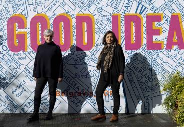 Ruth Sparkes and Sunita Gordon, co-founders of SaferSpace, dressed in black, photographed in harsh sunlight against a map of London with the slogan "Good Idea" printed over it.