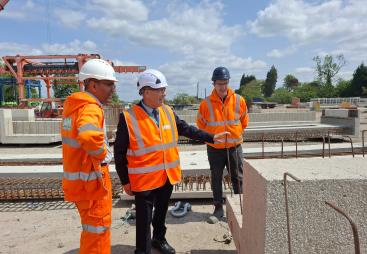 Three men in PPE, including Councillor Tony Eaton, chairman of Bassetlaw District Council, examine precast concrete elements in ABM Precast Solutions' yard during the company's 20th Anniversay celebrations.