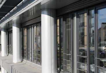A glass fronted office with concrete columns.