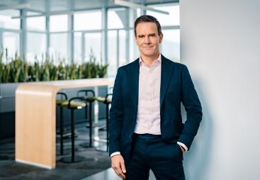 Dr Dominik von Achten, in dark suit and open neck shirt, standing in an empty office, has been elected the new president of GCCA, is chairman of the managing board at Heidelberg Materials
