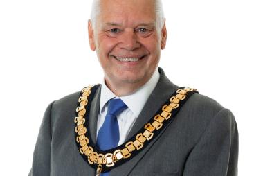 A photo of Paul Gandy, president, CIOB, wearing a grey suit, white shirt, blue tie and ceremonial chain.