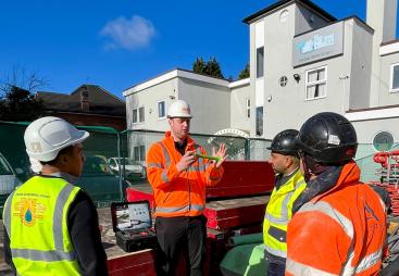 Men in a variety of PPE in front of a dental surgery discuss PERI UK and SWS's integrated waterproofing and formwork solution