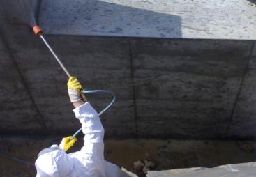 A man in white PPE Waterproofing underground sections of concrete with Vetrofluid using a low pressure pump.