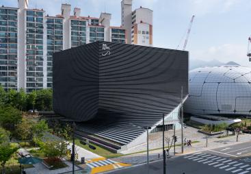 An exterior view of the Photography Seoul Museum of Art (Photo SeMA) features a distinctive twisted silhouette, created using a rhythmic layering of angled precast concrete panels.