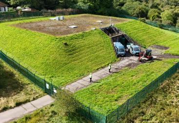 An aerial photo shows men in PPE and two vans at Stanley Hollowhouse following the installation of the cement-free, basalt-reinforced base for Scottish Water’s first verified Net Zero site.