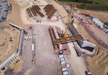 A yellow crane lifts beams into place for the Gloucestershire Way bridge, which will span the new A417 Missing Link and eight lanes of traffic