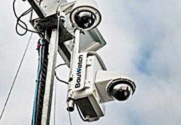 A close-up view looking up at two solar powered CCTV cameras mounted on a pole.