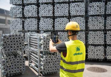A man in Doka branded PPE uses an AI device to count formwork elements