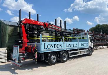 A blue London Lintels liveried truck with red loader crane mounted at the rear in London Lintels yard. London Lintels, now part of the Milbank Group, distributes concrete and steel lintels to customers across London and the South.