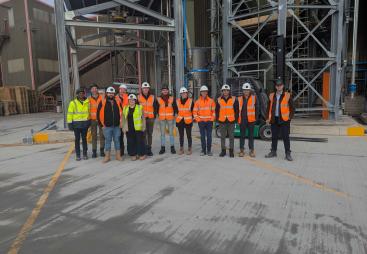 A group of people in yellow and orange PPE from Material Evolution, CRH, CRH Ventures & Tarmac at the Mevo A1 Production Facility in Llay, Wales